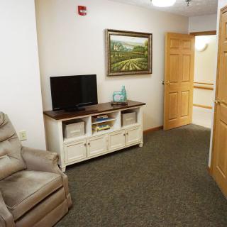 A cozy living room featuring a recliner, television, and framed artwork.