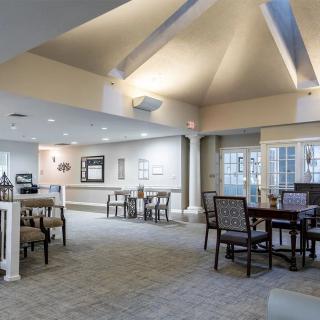 A spacious dining area with several tables and chairs, featuring a high ceiling with modern lighting.