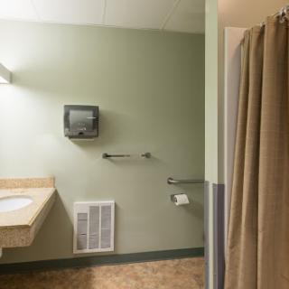 A spacious bathroom featuring a shower, sink, and accessible facilities.