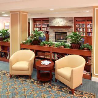 A cozy library lounge with plush seating, bookshelves, and a fireplace.