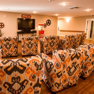 A cozy home theater setup featuring patterned armchairs and a large television.