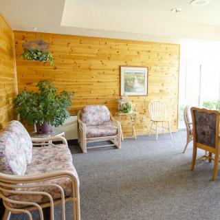 A cozy living room with wooden paneling, comfortable seating, and plants.