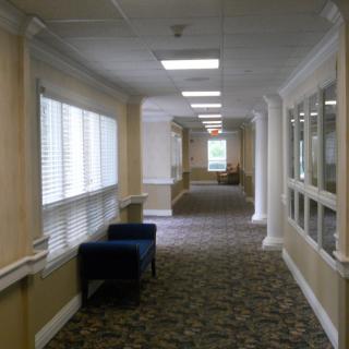 A long, carpeted hallway with windows and seating along the sides.