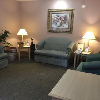 A cozy waiting room with sofas, lamps, and a decorative painting on the wall.
