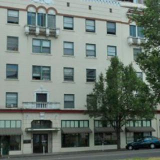 A multi-story urban building with trees lining the street in front.