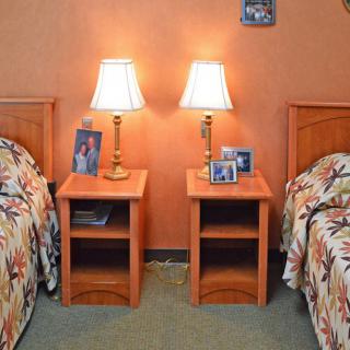 A cozy bedroom with twin beds, each flanked by nightstands topped with lamps and framed photos.