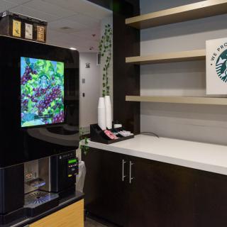 A modern coffee station with a coffee machine and empty shelves.