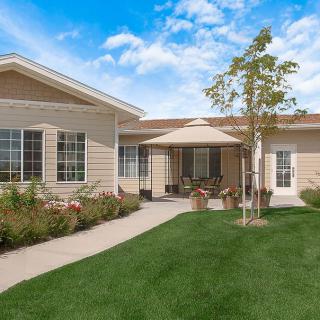 A single-story residential house with a garden and well-maintained lawn on a sunny day.