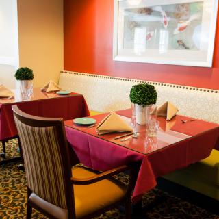 A cozy restaurant interior with neatly set tables and decorative plants.