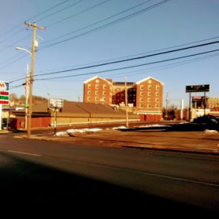 A view of an urban landscape featuring a multi-story building and a gas station along the road.