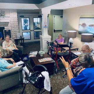 A group of seniors engaged in a lively discussion in a community lounge.