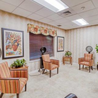 A cozy waiting room with striped chairs, decorative plants, and framed artwork on the walls.