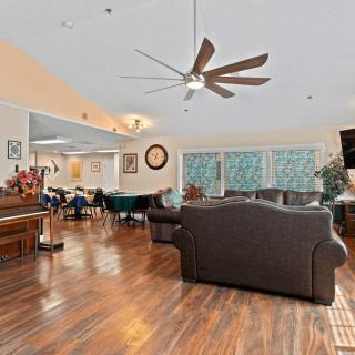 A spacious living room with a ceiling fan, hardwood floors, and comfortable seating.
