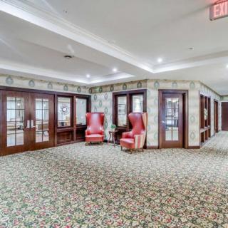 A cozy lobby area with red chairs and decorative carpet, featuring wooden doors and an illuminated exit sign.