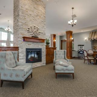 A cozy living room interior featuring a fireplace, elegant seating, and decorative chandeliers.
