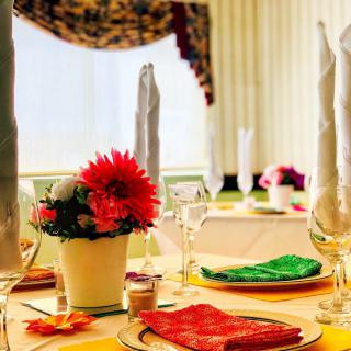 An elegantly set dining table with bright floral centerpiece and colorful napkins.