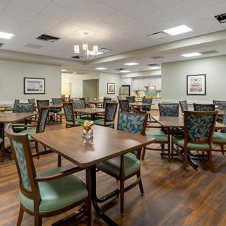 An empty dining room with modern decor and neatly arranged tables and chairs.