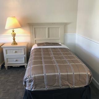 A cozy bedroom with a single bed, nightstand, and lamp.