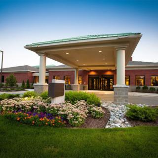 A well-landscaped building entrance with columns and flowerbeds.