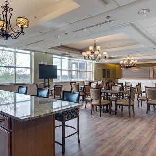 A modern dining room with elegant chandeliers, wooden flooring, and neatly arranged tables and chairs.