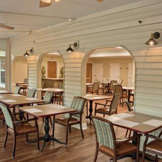 An indoor dining area with neatly arranged tables and chairs on a wooden floor.