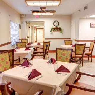 An elegant dining area with neatly arranged tables and chairs, adorned with folded napkins.