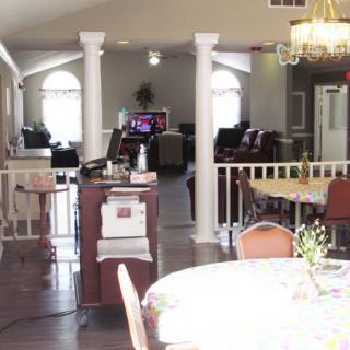 A spacious interior featuring a dining area with a table, chairs, and an open layout connecting to a reception space.