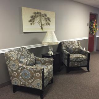 A cozy waiting area featuring patterned chairs and a soft lamp.