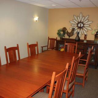 A well-furnished dining room with a large wooden table and chairs, complemented by decorative items on the walls and sideboard.