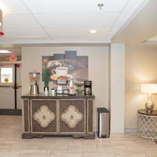 A cozy hotel lobby features a coffee station with various beverages and snacks.
