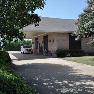 A suburban house with a car parked in the driveway surrounded by trees.
