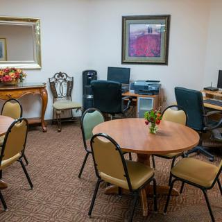 A small conference room with round tables, chairs, computers, and wall decorations.
