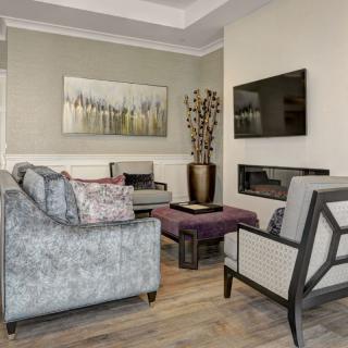 A modern living room featuring a comfortable sofa, armchairs, a wall-mounted television, and stylish artwork.