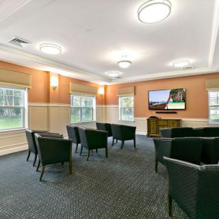 A spacious meeting room with multiple chairs and a television.