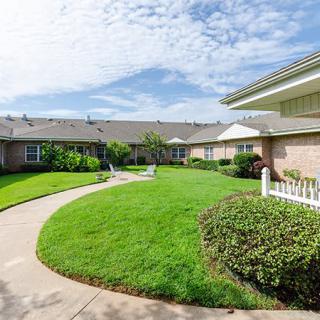 A well-maintained garden with a winding pathway in a residential area under a cloudy sky.