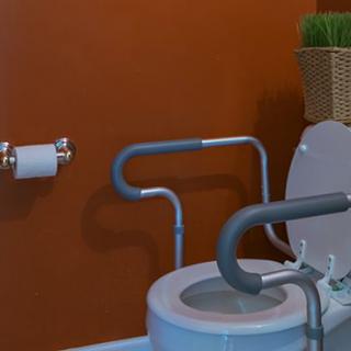 An accessible bathroom with safety grab bars and a toilet designed for ease of use.