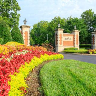 A beautifully landscaped entrance with vibrant flowers and brick pillars.