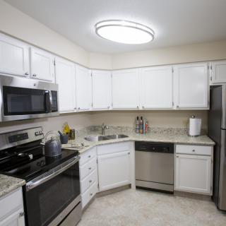 A modern kitchen with white cabinets and stainless steel appliances.