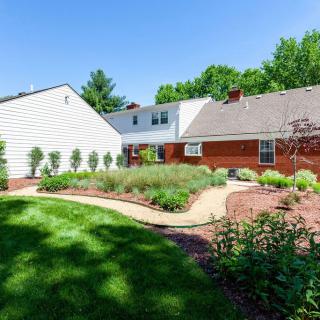 A well-maintained backyard featuring a garden with bushes and a neatly trimmed lawn.