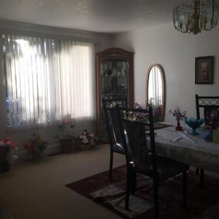 A dining room featuring a table with chairs, a china cabinet, and a mirror by the window.