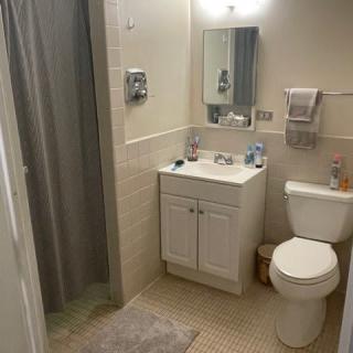A clean and organized bathroom with a sink, mirror, toilet, and shower.