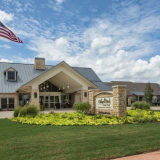 A well-maintained building with a landscaped entrance and an American flag flying in front.