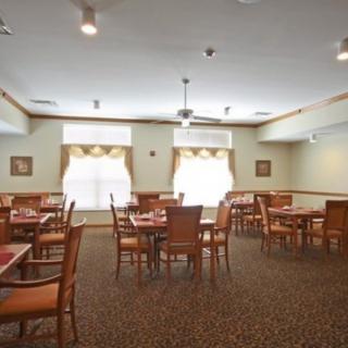 A well-lit dining room with several tables and chairs arranged neatly.