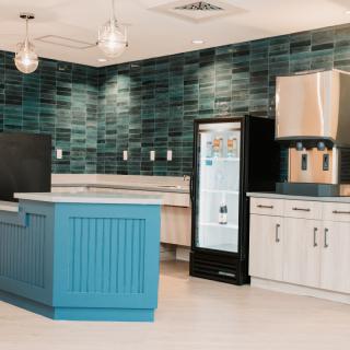 A modern kitchen featuring a blue island counter and stylish green tiled backsplash.