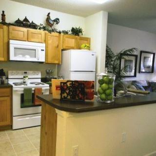 A cozy kitchen with wooden cabinets, featuring a white refrigerator, stove, and microwave. The countertop is adorned with decorative items.