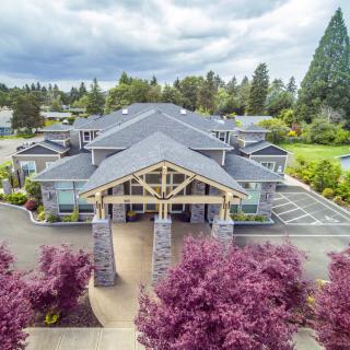Aerial view of a large building surrounded by trees with a cloudy sky overhead.