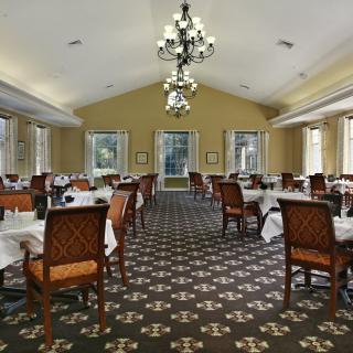 Elegant dining room with neatly arranged tables and a central chandelier.