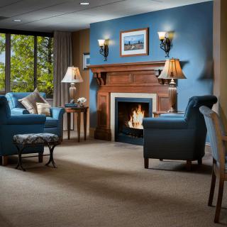 A cozy living room with blue walls, featuring a warm fireplace and comfortable armchairs.