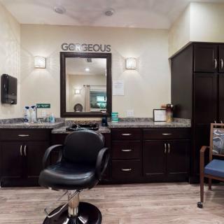 A modern hair salon interior with a styling chair, mirror, and cabinets.