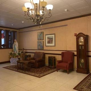 A cozy living room with a chandelier, armchairs, and a grandfather clock.